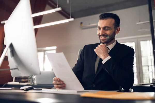 Nöjd ung chef läser dokument på sitt kontor — Stockfoto