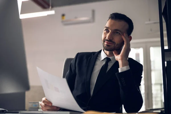 Hombre de negocios guapo está leyendo documentos en la oficina —  Fotos de Stock