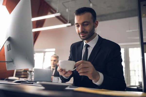 Caucásico atractivo hombre beber café en el lugar de trabajo en la oficina —  Fotos de Stock