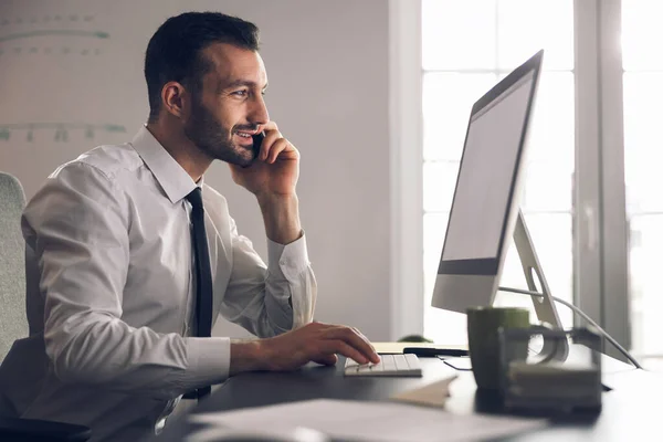 Bearded Caucasian man talking on smartphone in office — Stock Photo, Image