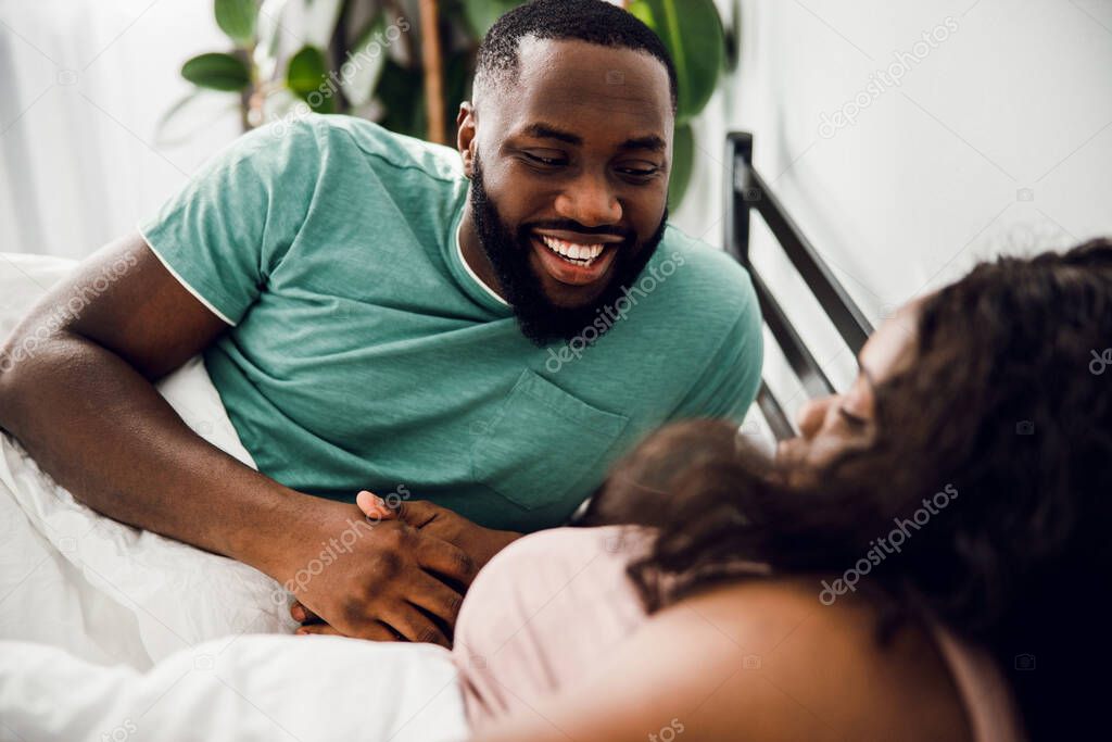 Positive man in bed with his woman stock photo
