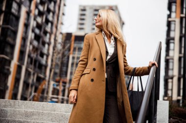 Sakin orta yaşlı bir kadın merdivenlerde dikiliyor.