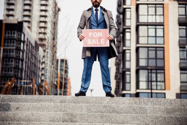 Şık bir adam yeni bir yerleşim yeri ilanı veriyor.