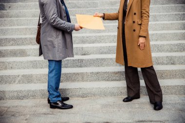 Kadın, erkek girişimciye zarf veriyor.