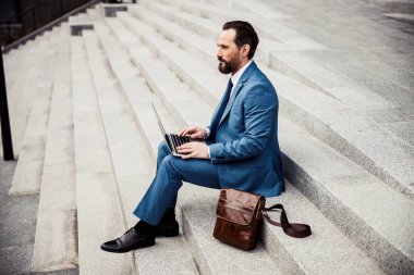 Sakin işadamı dışarıda merdivenlerde oturuyor.