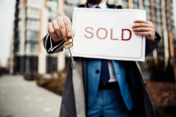 Male broker holding a sold sign outdoors — Stock Photo, Image