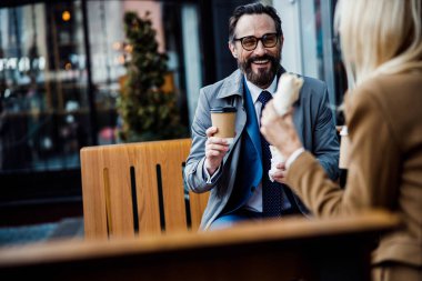 İş ortakları açık bir kafede yemek yiyor.