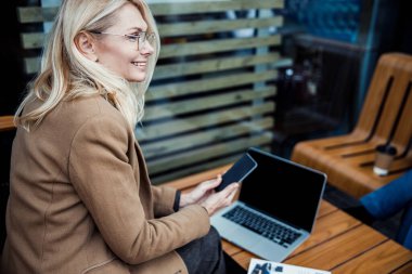 Akıllı telefonu elinde tutan neşeli bir kadın.