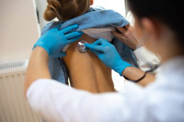 Kadın çocuk doktoru küçük çocuğu hastanede muayene ediyor.