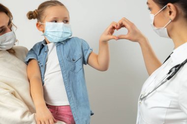 Kafkasyalı anne ve çocuğu klinikte tıbbi maske takıyor.