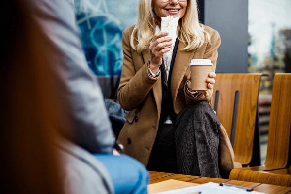 Leende kvinna sitter med sin kollega på ett café — Stockfoto