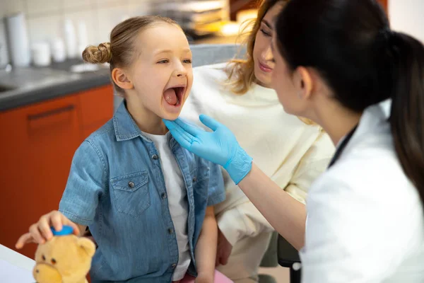 Kaukasischer Arzt in Gummihandschuhen bei der Kehlkopfuntersuchung im Krankenhaus — Stockfoto