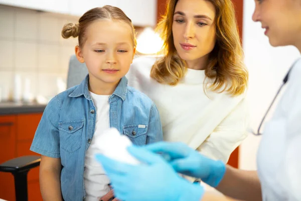 Kaukasisches Mädchen sitzt auf Knien ihrer Mutter im Krankenhaus in der Nähe des Arztes — Stockfoto