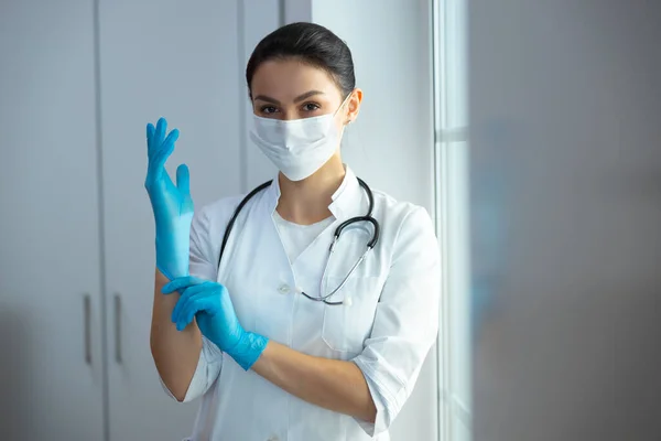 Caucásico médico femenino que se pone guantes de goma médica en la clínica — Foto de Stock