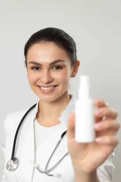 Beautiful happy doctor advertising bottle with medicine in arm — Stock Photo, Image