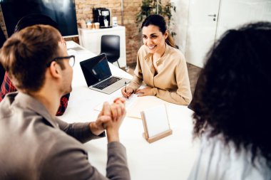 Ofiste iş arkadaşlarıyla çalışan çekici genç bir kadın.