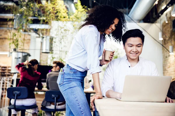 Vidám fiatal férfi és nő használja laptop a munkahelyen — Stock Fotó