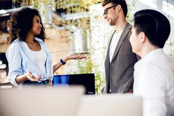 Encantadora joven hablando con amigos masculinos — Foto de Stock