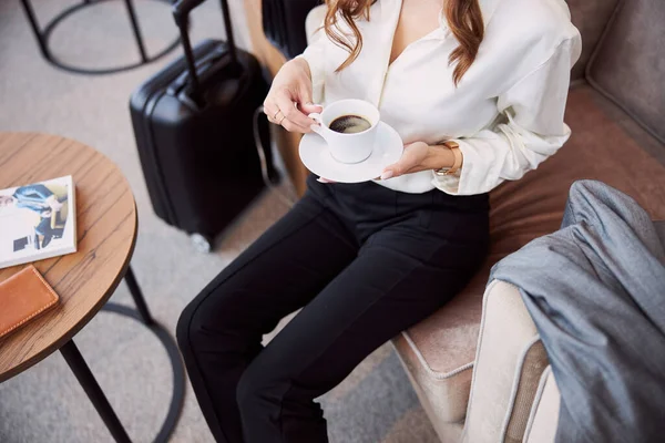 Молодая женщина пьет кофе в зале ожидания аэропорта — стоковое фото