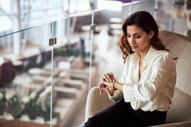 Güzel bayan sandalyede oturuyor ve zamanı kontrol ediyor.