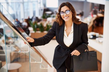 Zarif bir çanta taşıyan gözlüklü neşeli güzel bayan.