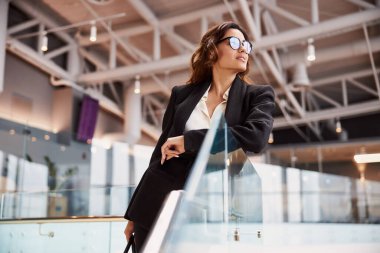 Çekici genç kadın cam korkuluklara yaslanıyor.