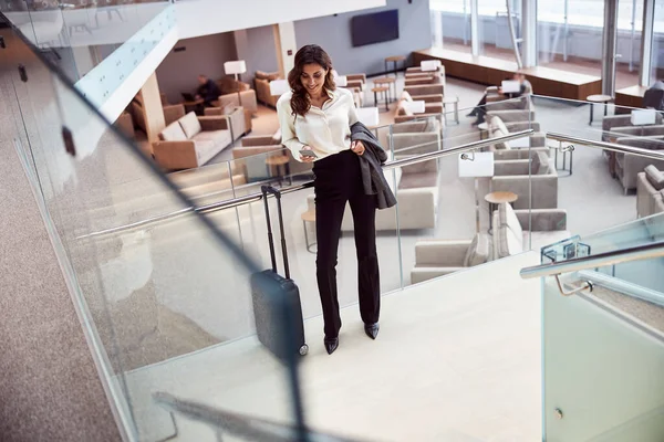 Bella signora utilizzando il cellulare in piedi in sala d'attesa aeroporto — Foto Stock