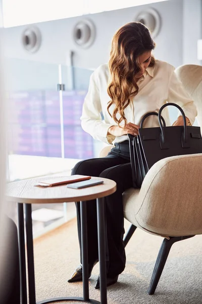 Mulher bonita procurando algo em sua bolsa — Fotografia de Stock