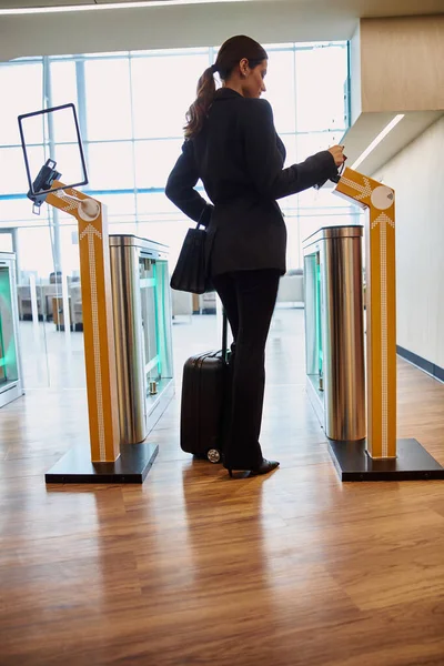Young woman passing electronic turnstile at airport
