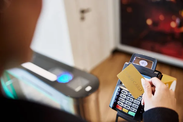 Mladá dáma používající zlatou kartu pro bezkontaktní platbu — Stock fotografie