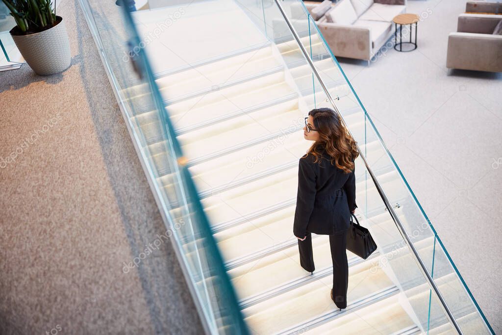 Stylish young woman climbing stairs in business center