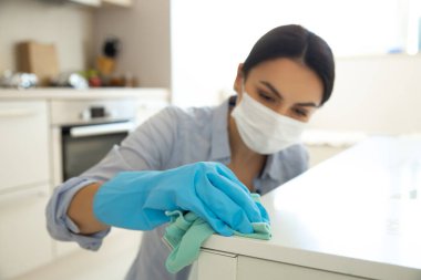 Ev hanımı mutfakta spreyle antivirüs temizliği yapıyor.