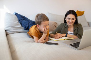 Sevgi dolu anne, oğlunun online çalışmasına yardım ediyor.