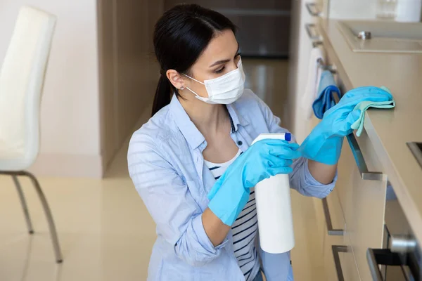 Mujer joven limpieza cocina con spray desinfectante — Foto de Stock