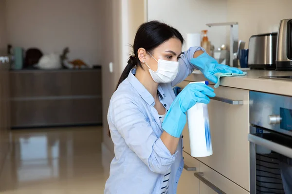 Mujer haciendo rutina del hogar con desinfectante en la cocina —  Fotos de Stock