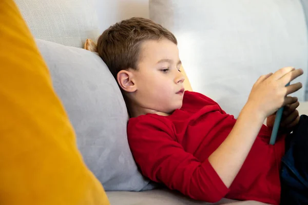 Niño jugando juegos interactivos en el sofá — Foto de Stock