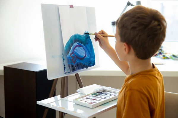 Bonito menino desenho com tintas azuis em casa — Fotografia de Stock