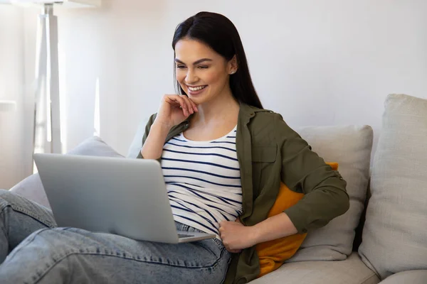 Charmig ung kvinna som använder laptop hemma — Stockfoto