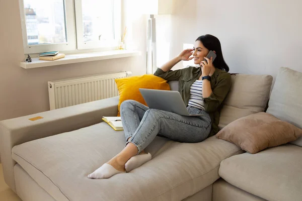 Çekici kadın kanepede uzanıyor ve cep telefonuyla konuşuyor. — Stok fotoğraf