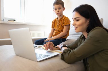 Sevimli küçük çocuk ve annesi evde defter kullanıyorlar.