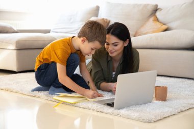 Huzurlu bir anne oğlunun defter defterine resim yazmasını izliyor.