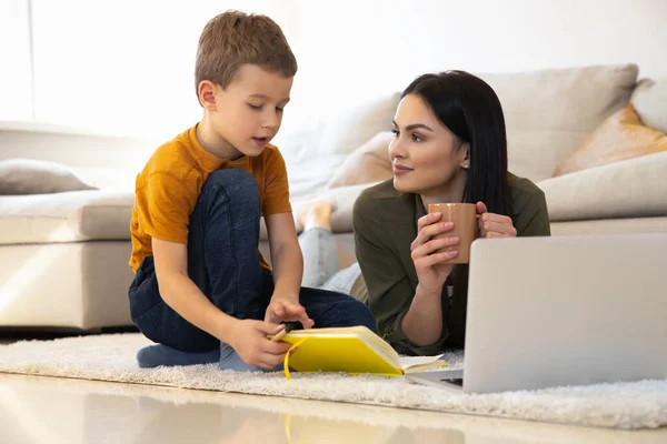 Sorrindo mãe bebendo chá e ouvindo seu filho pequeno foto stock — Fotografia de Stock