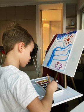 Evde boyaları olan şirin bir çocuk.