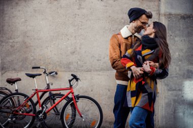 Güzel bir çift sokakta öpüşüyor ve gülümsüyor.