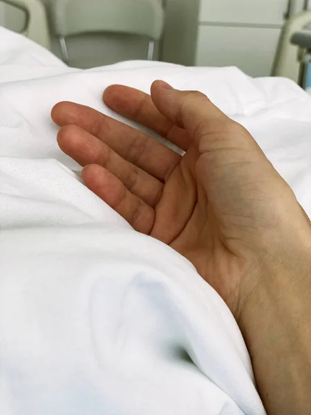 Young woman hand resting on hospital bed — Stock Photo, Image