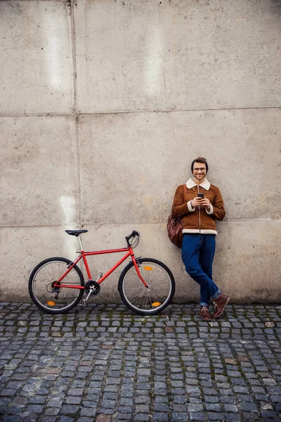 Mirthful fietser ontspannen door de muur buiten en glimlachen — Stockfoto