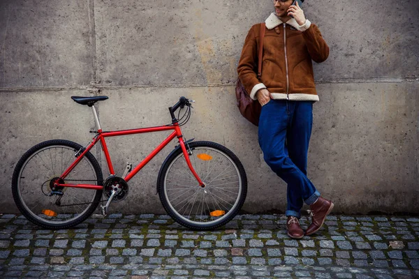 Uomo sorridente che parla al telefono all'aperto vicino alla sua moto stock foto — Foto Stock