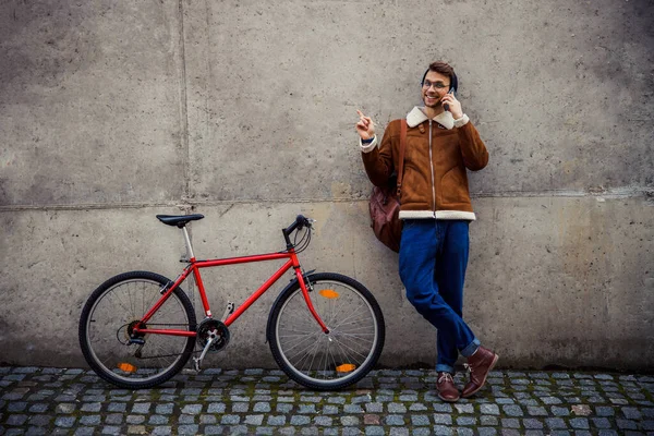 Glimlachende man die naar de muur wijst en aan de telefoon praat — Stockfoto