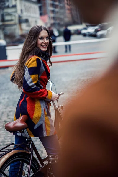 Mujer positiva con una bicicleta en la calle sonriendo foto de stock — Foto de Stock