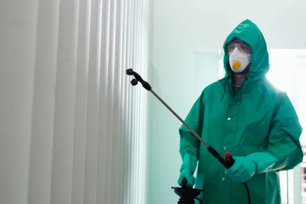 Дезинфицирующий работник в защитном костюме для дезинфекции на стенах — стоковое фото